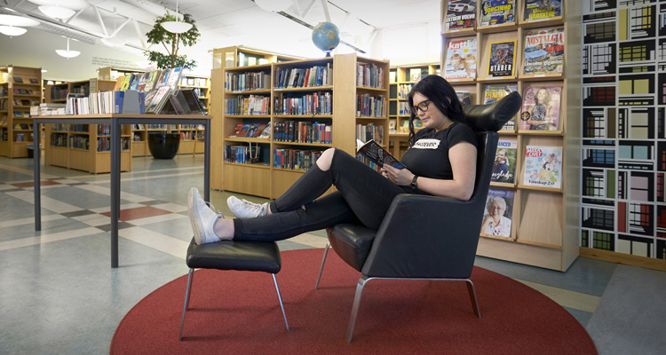Bild på en elev i ett bibliotek.